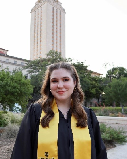 Student in graduation robe in front of the UT Tower.